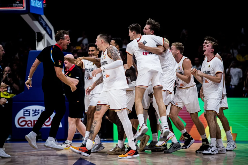 Jubelnd liegen sich die Jungs der deutschen Basketball-Nationalmannschaft und ihr Therapeut Frank Offermann in den Armen – nach einem Sieg gegen die Serben, der sie zum Weltmeister 2023 machte.